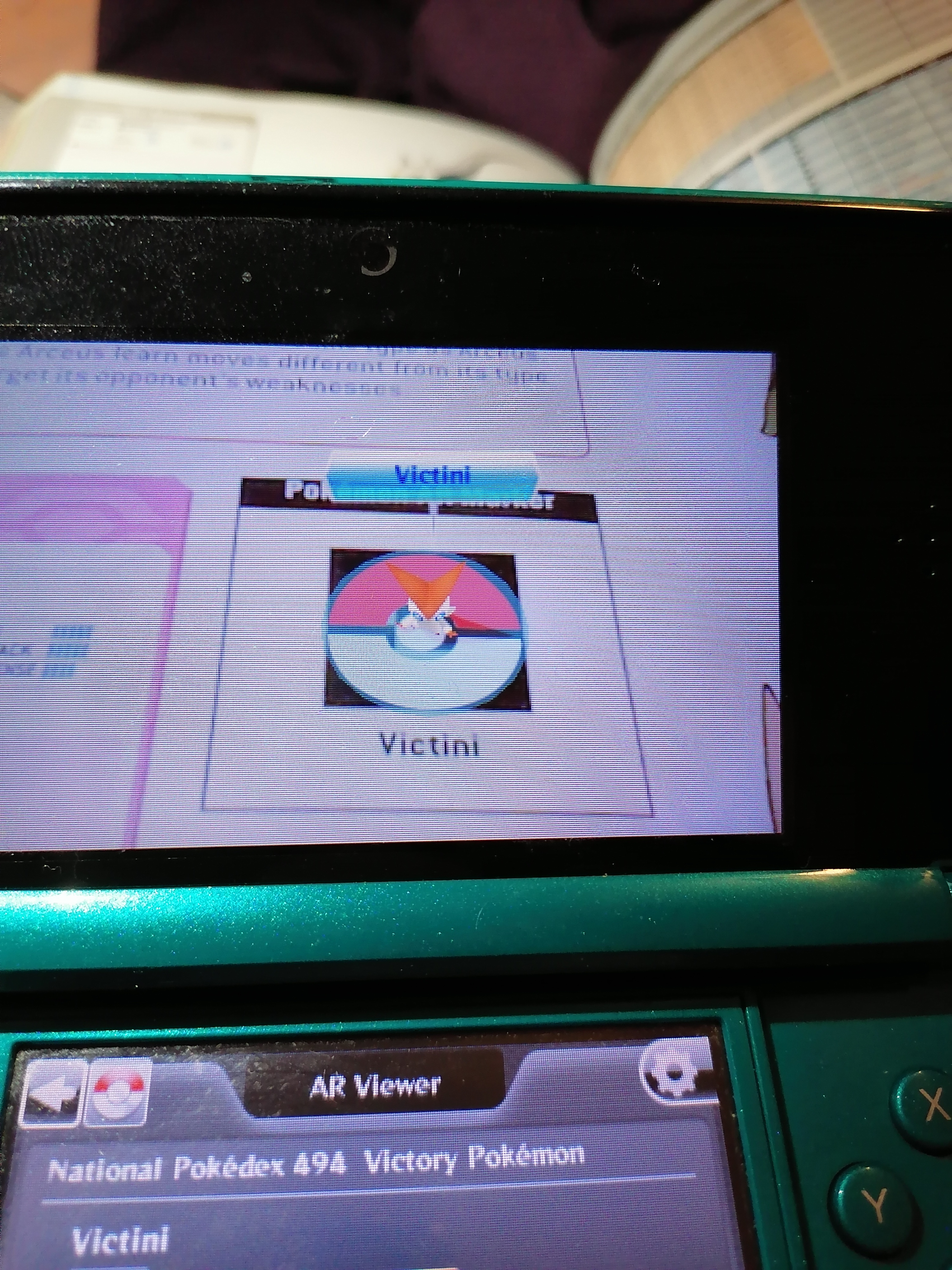 image 3ds screen which is live superimposing a 3d model of victini above its marker on the page of the book