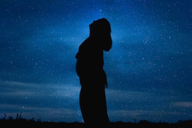 A siloutte of a woman in the night sky.